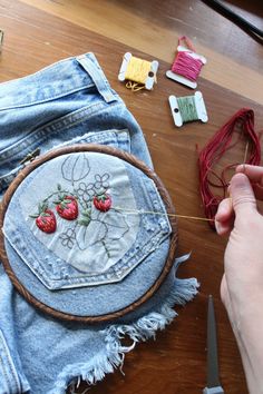 someone is stitching something on the back of some jean shorts with scissors and thread