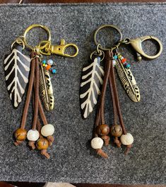 two key chains with different colored beads and leaves on them sitting on top of a table