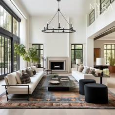 a living room filled with lots of furniture next to tall windows and a fire place