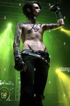 a man with tattoos and piercings on his chest performing at a concert - stock image