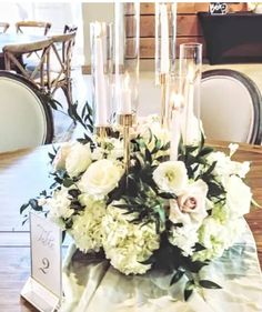 a centerpiece with flowers and candles on a table