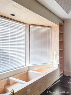 an unfinished window seat in the corner of a room that is being built with plywood