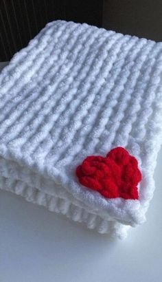 a white knitted blanket with a red heart on it