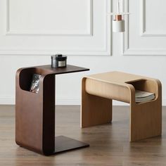 two wooden tables with magazine holders on them in front of a white wall and wood floor