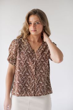 Introducing the 'Sabrina' button down top – a delicate and charming addition to any ensemble. This top is adorned in a ditsy floral pattern that is simple yet stunning! Pair with a pencil skirt and low heels for a simple and sophisticated office look. 100% Polyester Lined Hand Wash Cold Hang or Lay Flat to Dry Do Not Bleach Cool Iron If Needed Functional, nursing friendly buttons! FINAL SALE: NOT ELIGIBLE FOR RETURN OR EXCHANGE Model Height 5'7" | Wearing Size Small Wearing the 'Sabrina' Ditsy F Feminine Brown Tops For Spring, Feminine Ditsy Floral Print Blouse For Day Out, Feminine Short Sleeve Tops With Ditsy Floral Print, Feminine Blouse With Ditsy Floral Print For Day Out, Trendy Ditsy Floral Print Top For Day Out, Summer Ditsy Floral Print Tops For Daywear, Summer Tops With Ditsy Floral Print For Daywear, Feminine Tops With Ditsy Floral Print, Feminine Floral Print Blouse For Daywear