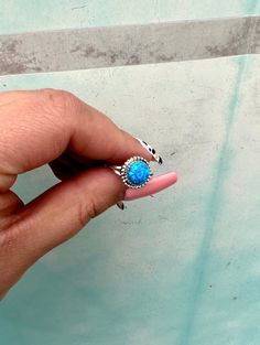 a person's hand holding a ring with a turquoise stone