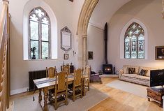 a living room filled with furniture next to two arched windows and a fire place in the corner