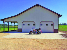 two motorcycles are parked in front of a large white building on the side of a dirt road