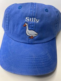 Looking for a fun and quirky accessory to add to your everyday look? Look no further than the None Silly Goose Dad Hat! Crafted from high-quality materials by trusted maker Port Authority, this washed blue hat is the perfect way to add a touch of humor to your outfit. The hat's playful design features a silly goose graphic front and center, adding an element of lighthearted fun that's sure to turn heads. With its comfortable fit and adjustable strap, this Dad Hat is perfect for any casual occasi Cheap Fun Blue Hats, Blue Cotton Hat With Short Brim, Denim Blue Baseball Cap For Spring, Trendy Adjustable Soft-washed Hat, Blue Denim Baseball Cap With Curved Brim, Trendy Washed Baseball Cap For Summer, Denim Curved Bill Hats For Spring, Spring Blue Denim Baseball Cap, Washed Blue Cotton Cap