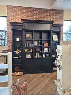 a large black bookcase with lots of books on it's shelves in front of a brick wall