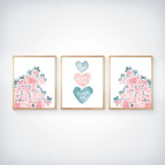 three pink and blue hearts are hanging on the wall in front of two framed pictures