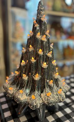 a small christmas tree made out of rocks on a black and white checkered tablecloth