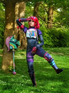 a woman with red hair is standing in the grass next to a tree and holding an umbrella