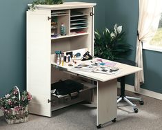 a white desk sitting in the corner of a room next to a potted plant