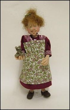 a doll with red hair is holding a small bird in her hand and wearing an apron