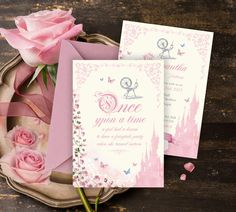 two pink roses are sitting on a table next to some cards and envelopes that say once upon a time