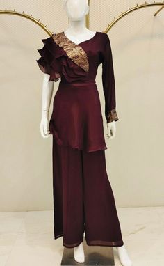 A sophisticated Indo-Western palazzo set in a chocolate brown hue, featuring both a top and bottom. The plain top is gracefully designed with a single full-length sleeve, while the opposite sleeve is tastefully adorned with delicate ruffles. The neckline is embellished with sequin embroidery on one side, perfectly complementing the eloquent elbow sleeve. The set is completed with plain palazzo pants, ensuring comfort throughout the day. Note: Colors may slightly vary due to photographic lighting Fitted Pant Set For Eid And Formal Occasions, Fitted Pant Set For Formal Eid Celebrations, Fitted Pant Set For Eid, Formal Fitted Pant Set For Eid, Elegant Full-length Sets For Eid, Elegant Full Length Sets For Eid, Elegant Long Sleeve Set For Wedding Guest, Elegant Formal Pant Set For Eid, Formal Long Sleeve Pant Set For Eid