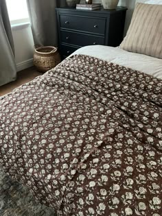 a bed with brown and white bedspread in a bedroom next to a window