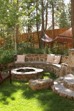 a stone fire pit in the middle of a grassy area with hammock chairs