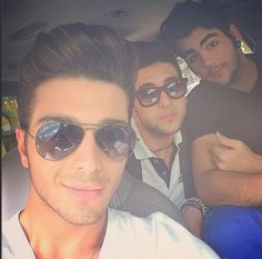 three men sitting in the back seat of a car with one man taking a selfie