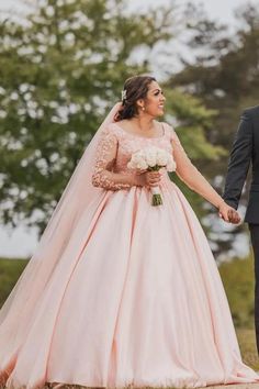 a bride and groom holding hands in front of trees