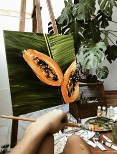 a person is painting on an easel next to a plant