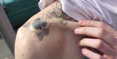 a person with a tattoo on their back holding his hand up to the side of his shoulder