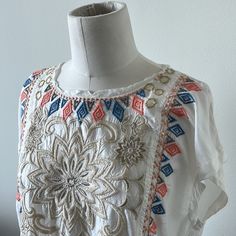 Nwt Beautiful Johnny Was Embroidered Cap Sleeve Top. Ivory (Jw Color States “Natural”) Background With Multi Colored Embroidered Florals And Geometric Designs. Please See Close Up Pictures For All The Fabulous Details With Metallic And Soft Playful Colors. This Top Has Small Pockets In The Front (Also Pictured Close Up) And A Raw Edge Cool Neck Detail. Easy To Dress Up Or Down!! This Is A Forever Classic Piece With Its Incredible Detailing!! Embroidered Cream Top For Festival, Embroidered Cream Tops For Festival, White Short Sleeve Tops With Tonal Embroidery, White Bohemian Embroidered Top For Summer, Summer Festival Floral Embroidered Fabric, White Bohemian Top With Tonal Embroidery, White Bohemian Tops With Tonal Embroidery, Traditional White Embroidered Summer Fabric, Cream Embroidered Tops For Vacation