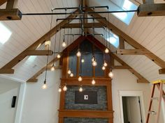 a room that has some lights hanging from it's ceiling and a fireplace in the middle