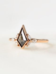 a gold ring with a black diamond and white diamonds on the side, set in 18k rose gold