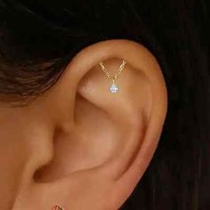 a woman's ear with a single diamond in the middle and two small diamonds on each side