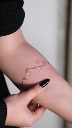 a woman's arm with a small tattoo on it