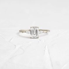 a white gold ring with an emerald cut diamond