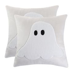 two white pillows with black eyes and one has a ghost face on the pillow cover