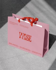 a pink shopping bag with a red ribbon tied around the handle that says purse balance, awareness identity