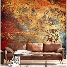 a couch sitting in front of a wall covered in rust and gold paint on it