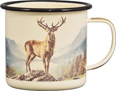 a white and black coffee mug with a deer on it's side, in front of mountains