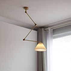 a lamp hanging from the ceiling over a bed in a room with white walls and curtains