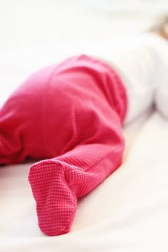 a baby is laying on the floor wearing a pink outfit