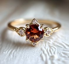 an orange and white diamond ring on top of a white cloth with diamonds around it