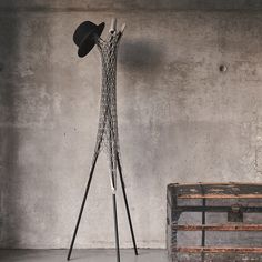 a hat is sitting on top of a metal stand next to an old box and trunk