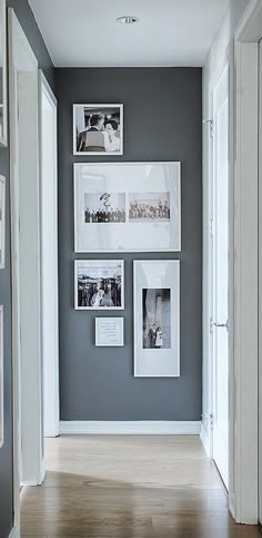 a hallway with pictures on the wall and wooden floors in front of it, along with white framed photos