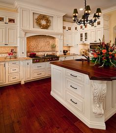 a large kitchen with white cabinets and wood flooring on the countertops, along with a center island