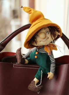 a small doll sitting in a brown purse