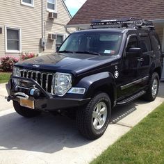 a black jeep parked in front of a house with a roof rack on it's flatbed