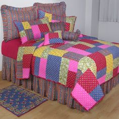 a bed with colorful bedspread and pillows on it in a room next to a rug