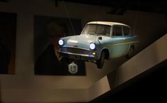 an old blue car suspended from the ceiling