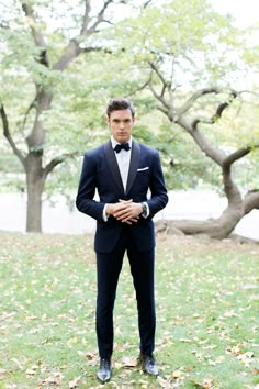 a young man in a tuxedo poses for the camera with his hands on his hips