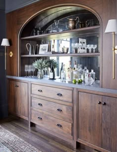 a wooden cabinet filled with lots of bottles and glasses on top of it's shelves