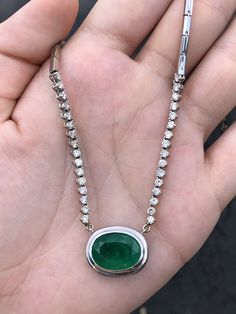 This necklace is not for the faint of heart! Featured here is a stunning oval Colombian emerald and diamond necklace made in fine 14K white gold. Displayed is a rich, dark green oval emerald with very good eye clarity for its huge 9.09-carat size. Brilliant round diamonds hug your neck with a sleek golden link chain that follows through the back. Setting Style: Prong/ Bezel Setting Material: 14k White Gold Stone: Colombian Emerald Shape: Oval Cut Luster: Very Good Color: Dark Green Saturation: D Formal White Gold Oval Emerald Necklace, Exquisite Oval Emerald Necklace For Formal Occasions, Oval Bezel Setting Necklace For Anniversary, Formal Oval Emerald Necklace In White Gold, White Gold Oval Cabochon Necklace For Anniversary, Classic Oval Gemstone Diamond Necklace, Classic Oval Diamond Necklace With Gemstone, Oval Emerald Jewelry With Diamond Cut, Exquisite Oval Diamond Necklace With Accents